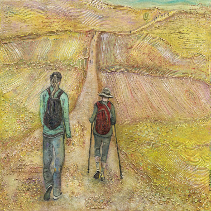 Two pilgrims walking the Camino trail through golden fields